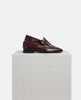 Pair of brown loafers on a white pedestal with a light gray background 4