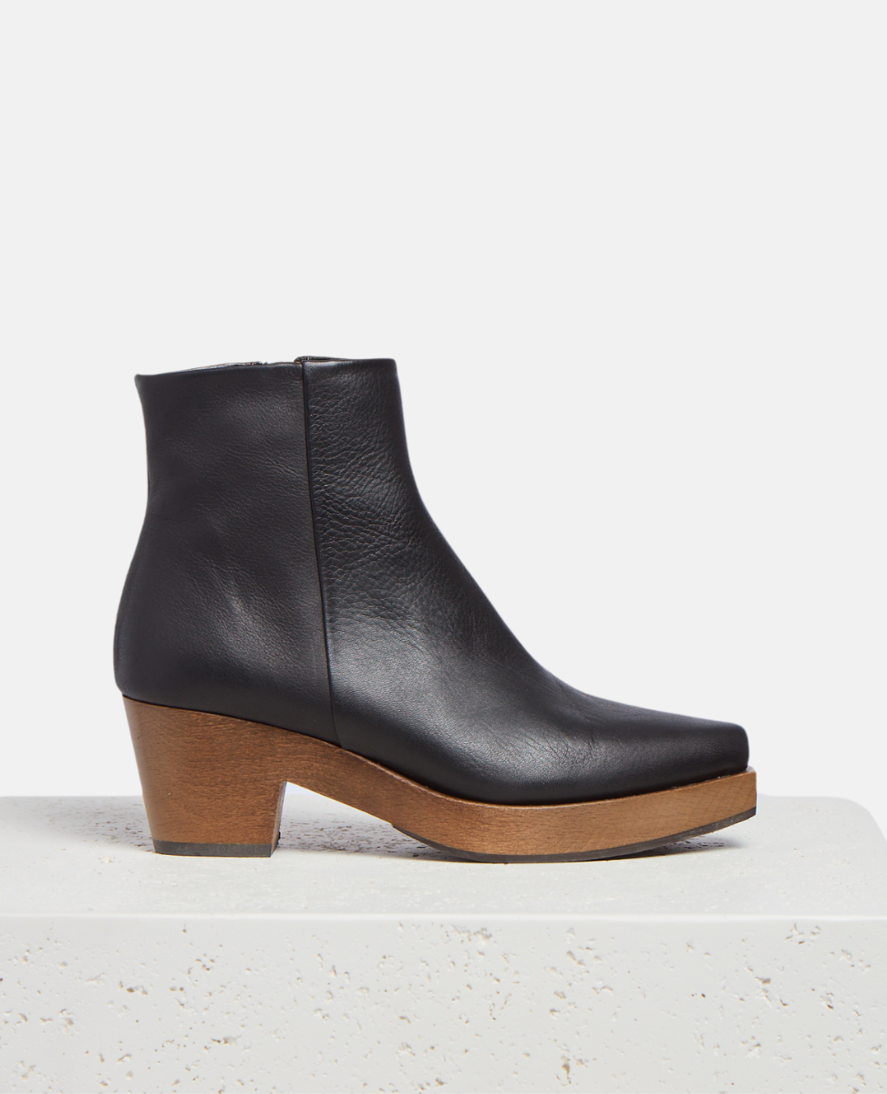 Black leather ankle boot with wooden sole on a light gray background