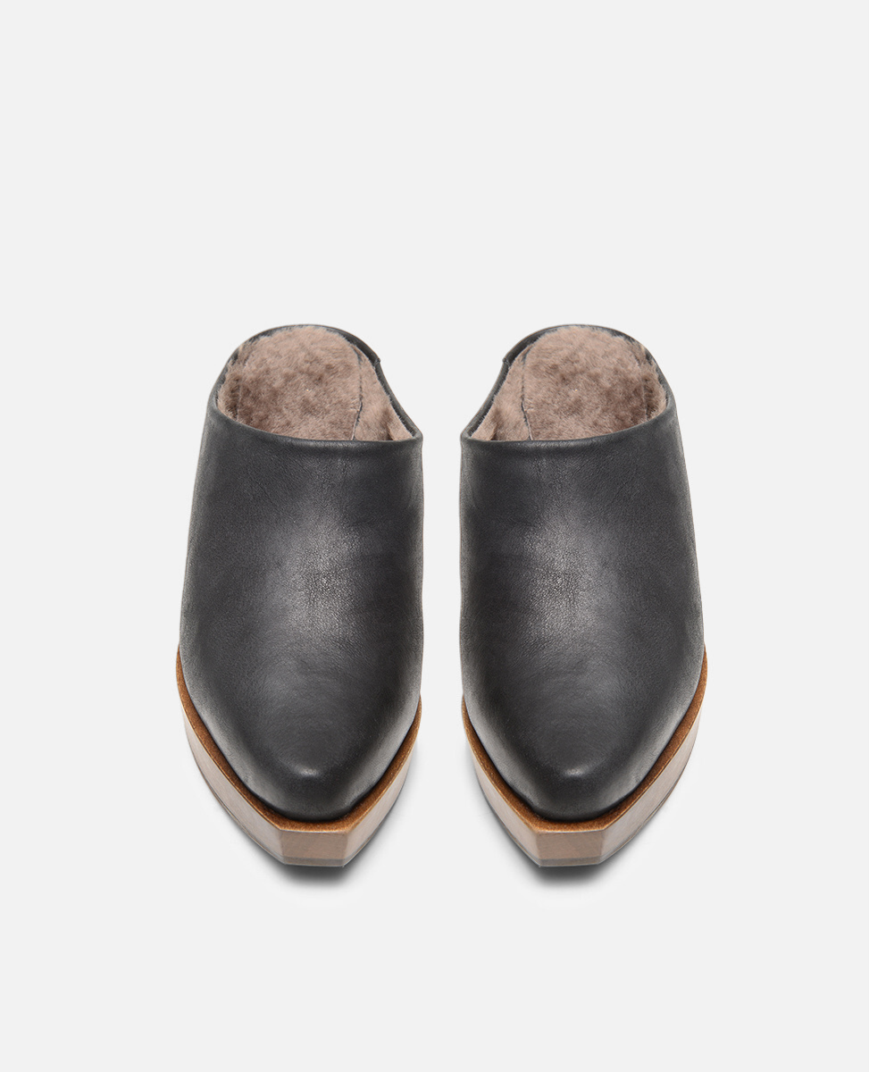 Pair of black leather clogs on a light gray background