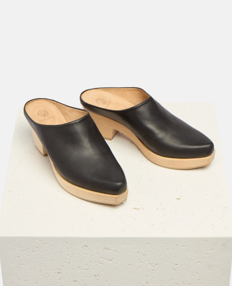 Pair of black leather clogs with wooden soles on a white background