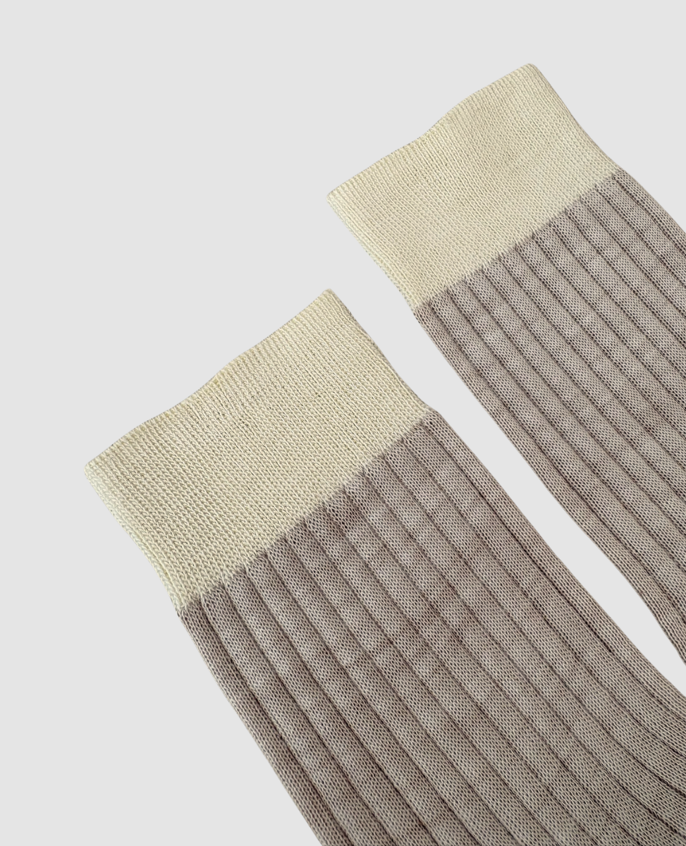Pair of ribbed socks with beige top and gray bottom on a light gray background