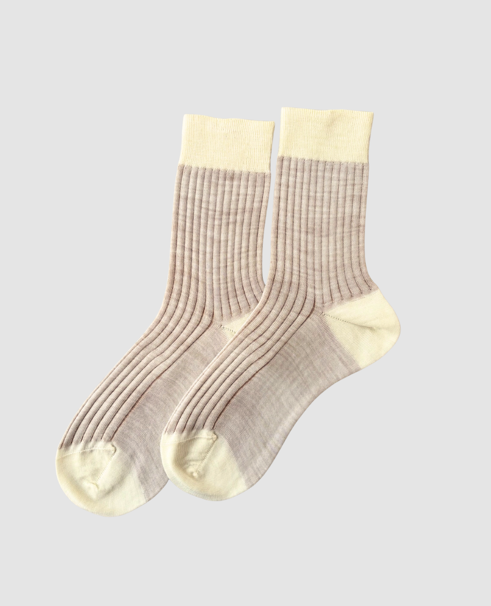 Pair of beige socks with white accents on a light gray background