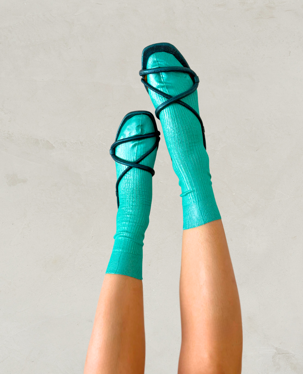 Pair of metallic foil aqua blue green silk socks by Maria La Rosa shown on the foot with a pair of Coclico blue metallic sandals