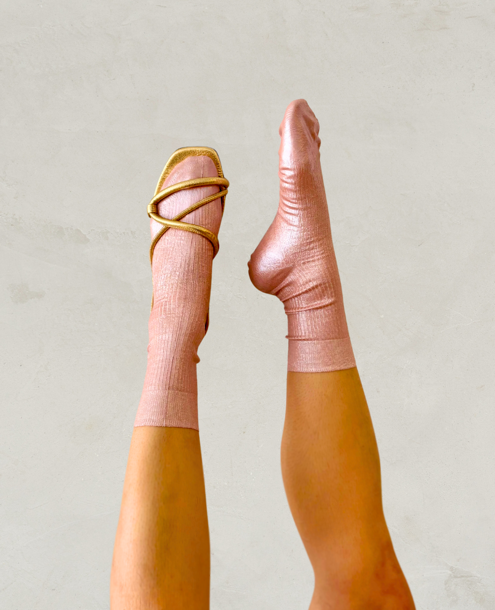 Pair of metallic foil pale pink silk socks by Maria La Rosa shown on the foot with a Coclico gold sandal