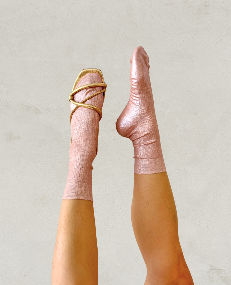 Pair of metallic foil pale pink silk socks by Maria La Rosa shown on the foot with a Coclico gold sandal