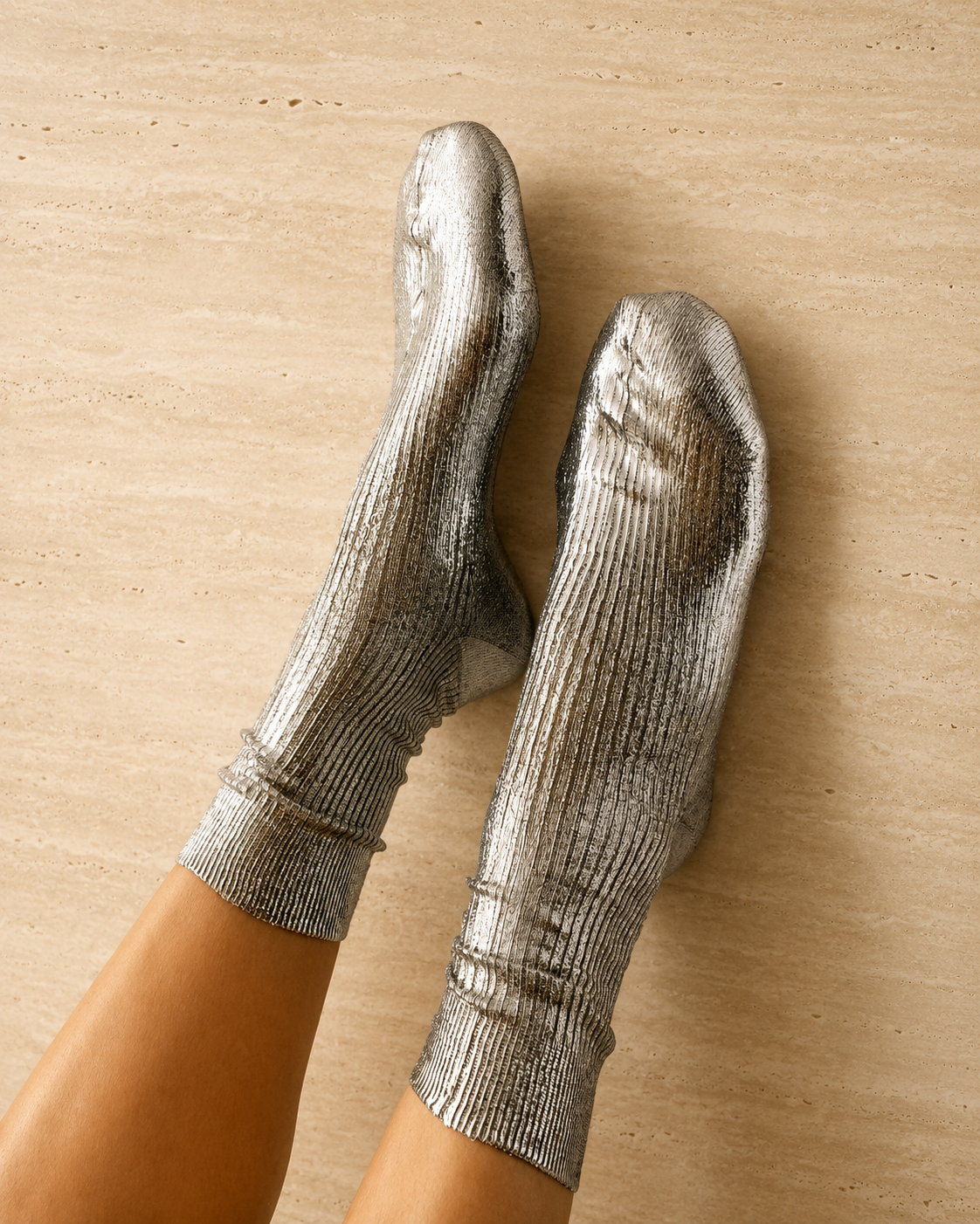 Shiny silver socks with a ribbed texture, mid-calf length, and a snug fit, made from a metallic, stretchy fabric.