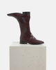 Pair of burgundy leather boots on a light gray pedestal against a white background 4
