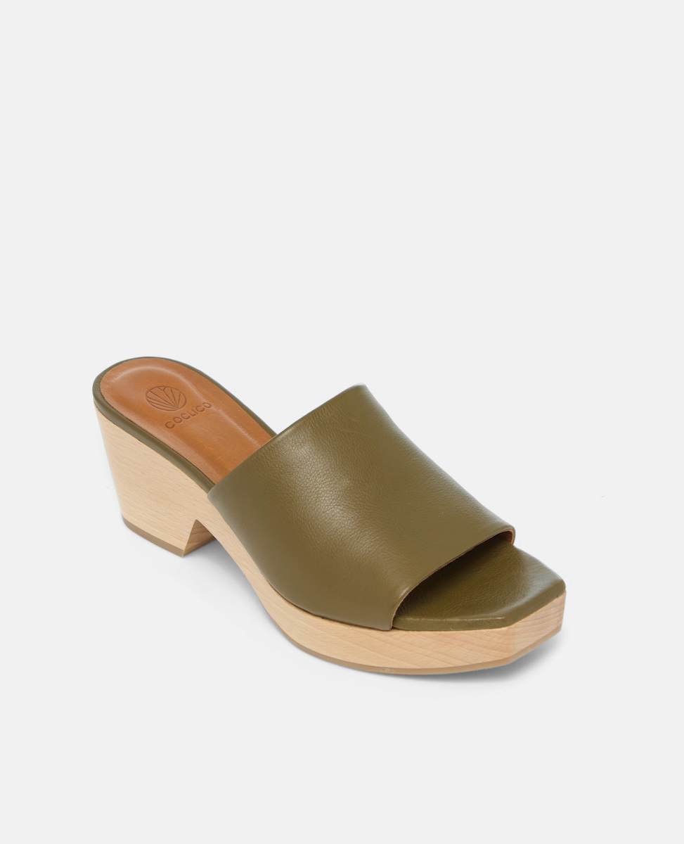 A stylish clog sandal featuring an olive green leather upper, an open toe design, and a light wooden block heel and platform. Angled View