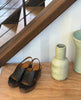 Coclico Moska Wedge in Deep Sea leather: Huarache inspired wedge sandals on a table with ceramics. 6