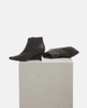 Pair of dark brown leather shoes on a textured white platform with a light gray background 4