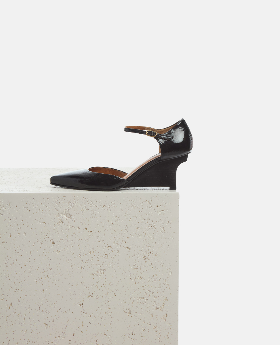 Black leather shoe on a light gray surface with a white background
