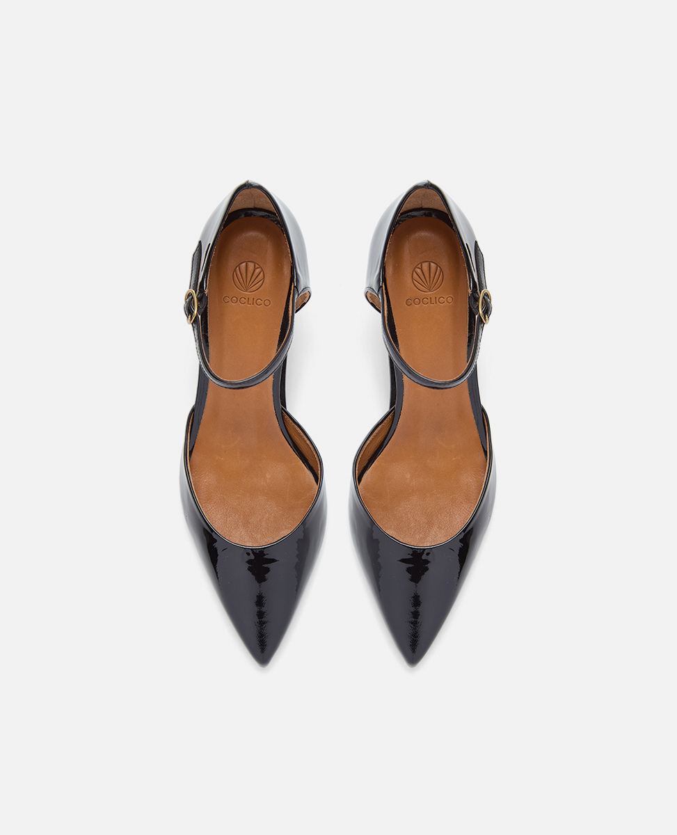 Black patent leather shoes with tan soles on a white background