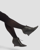 Black leather ankle boots worn with black tights on a light gray background 5
