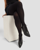 Person wearing black tights and shoes sitting on a white block against a light gray background 4