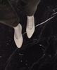 Regal Sneaker in greige on the foot, model standing on black marble 11