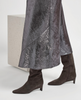 Person wearing a metallic silver skirt and brown knee-high boots on a white background 5