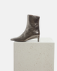Bronze ankle boot on a light gray pedestal against a white background 4