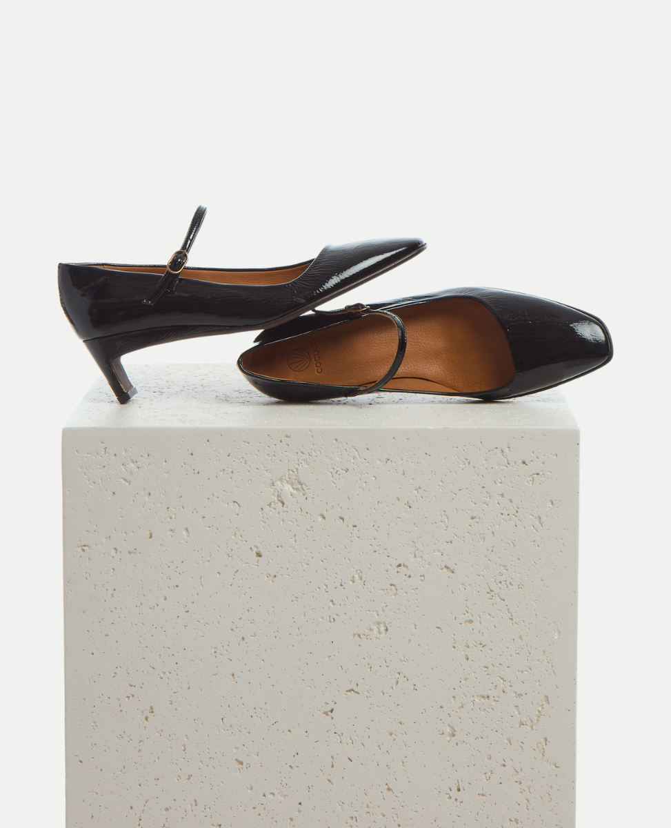 Black high-heeled shoes on a white pedestal