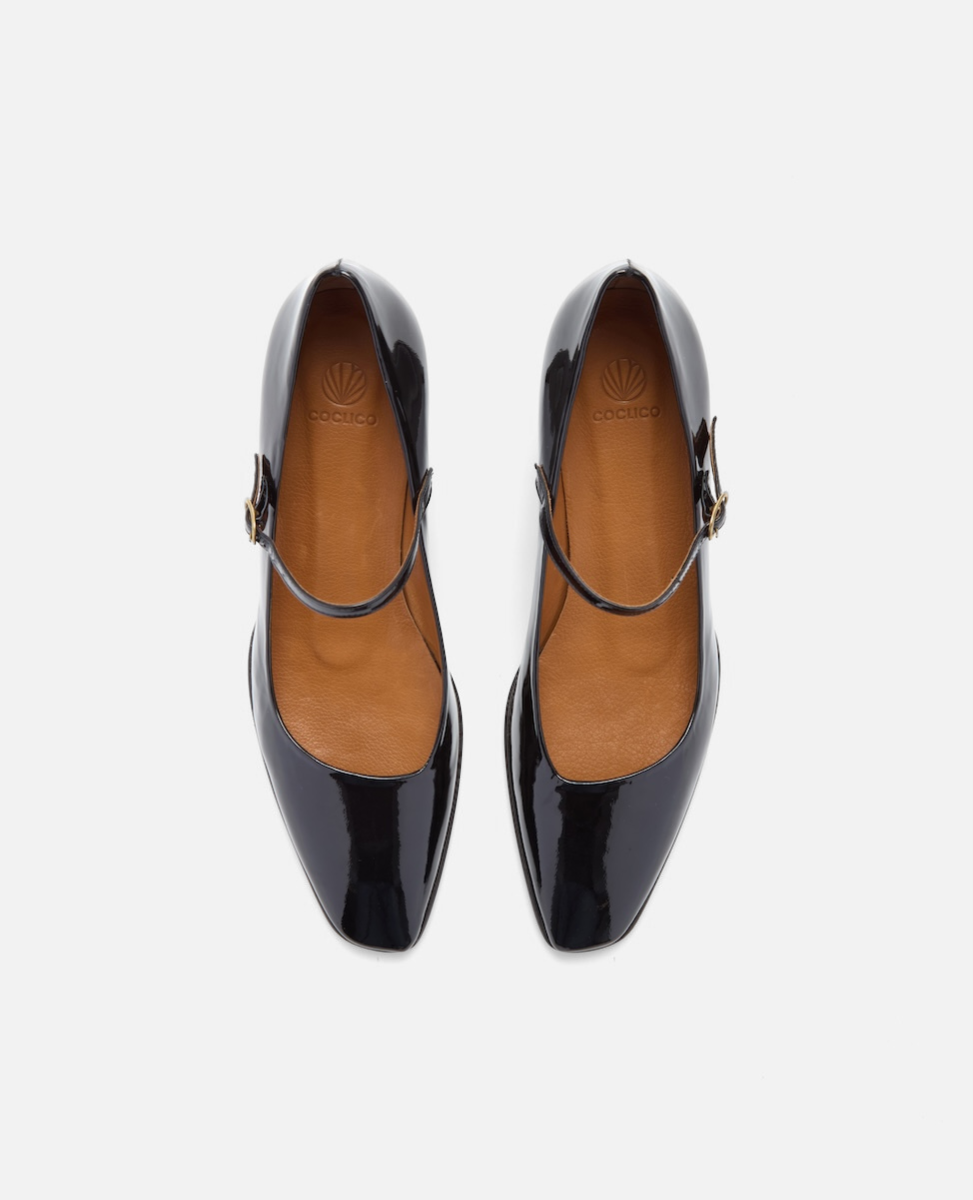 Black patent leather shoes with tan insoles on a white background