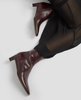 Brown leather ankle boots worn with black pants on a light gray background 6