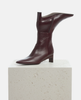 Burgundy leather boot on a light gray pedestal against a white background 4