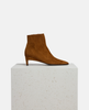 Brown suede ankle boot on a white pedestal with a white background 4