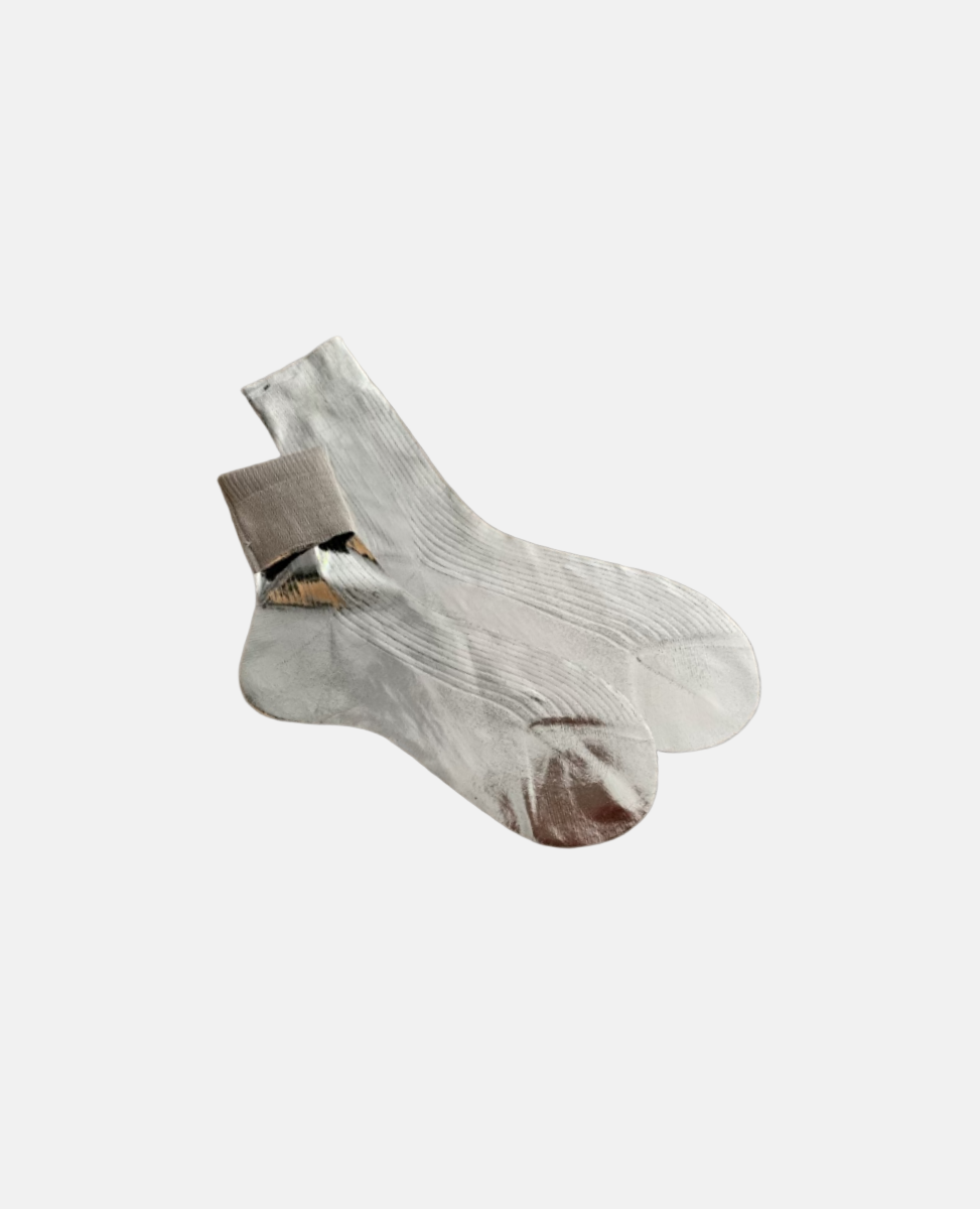 A pair of white, mid-calf socks with a ribbed texture, featuring a smooth, slightly shiny finish and a small, attached cardboard tag near the cuff.