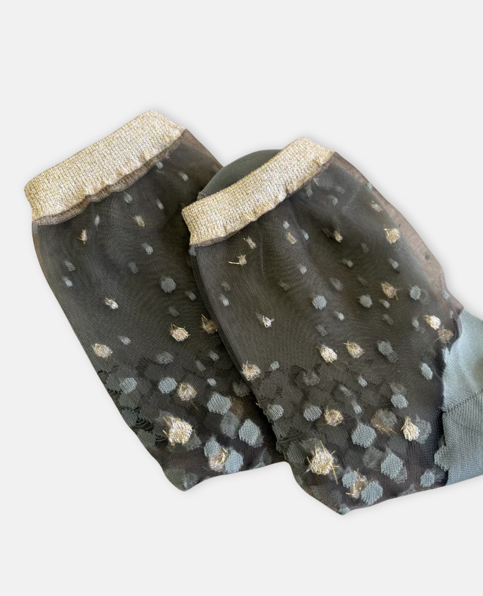 Pair of transparent gray socks with gold polka dots and trim on a white background