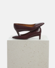 Brown high-heeled shoe on a light gray pedestal against a white background 4