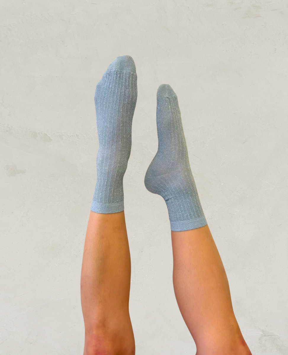 Light blue shimmery socks by Swedish Stockings worn by a person on a plain background