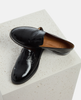 Black patent leather loafers on a light gray surface 5