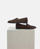 Pair of brown loafers on a light gray pedestal against a white background 4