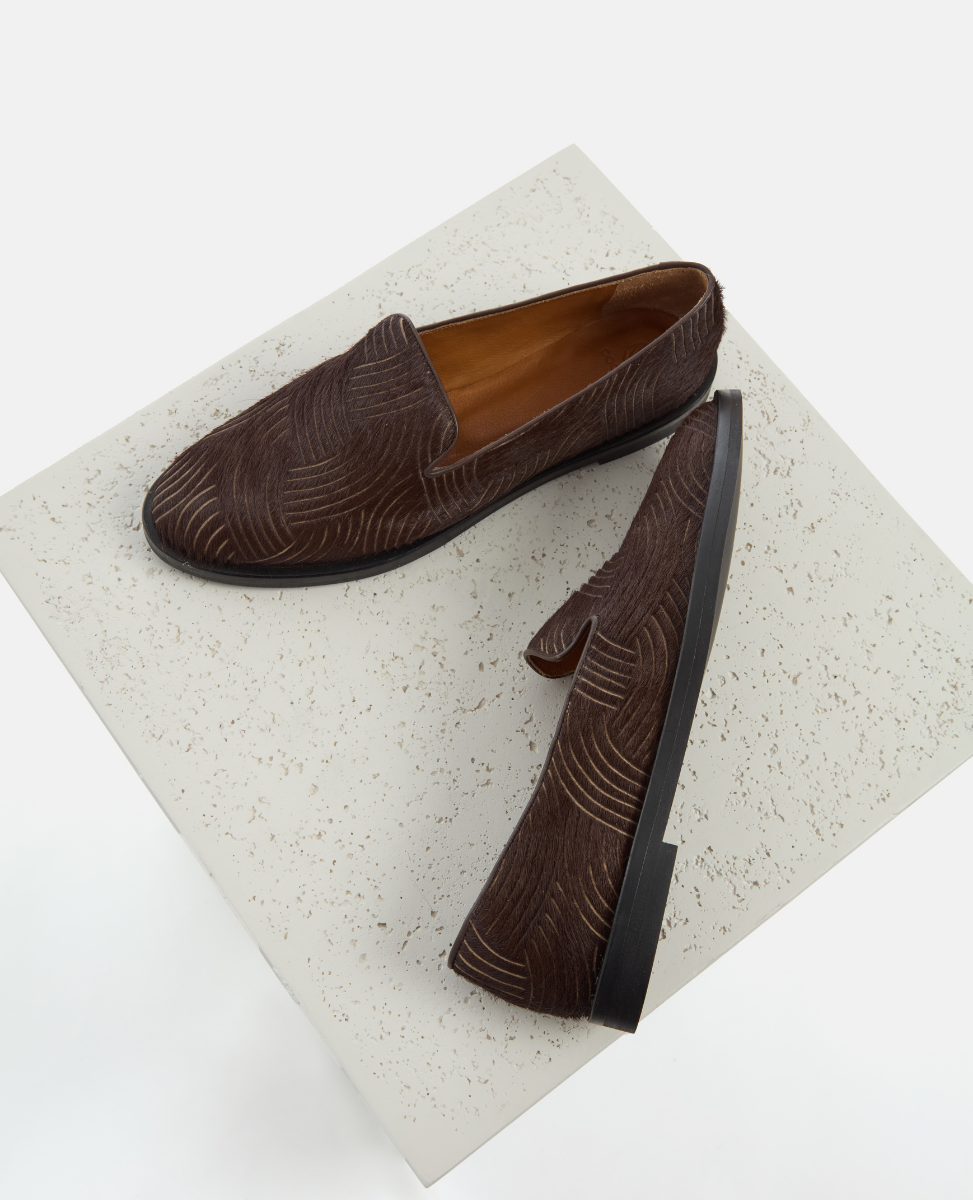 Pair of brown loafers on a textured white platform