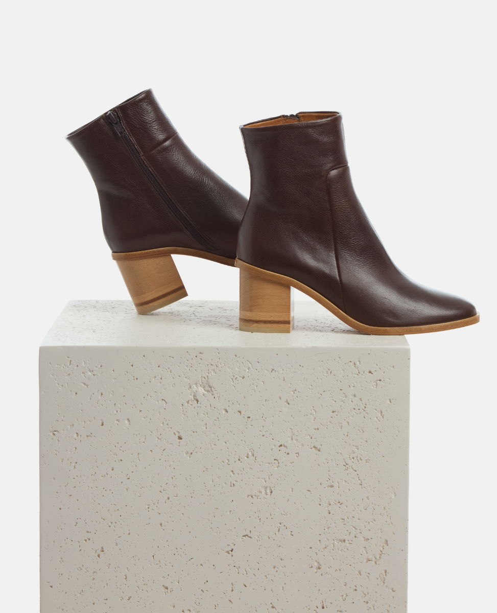 Pair of brown leather ankle boots on a white pedestal