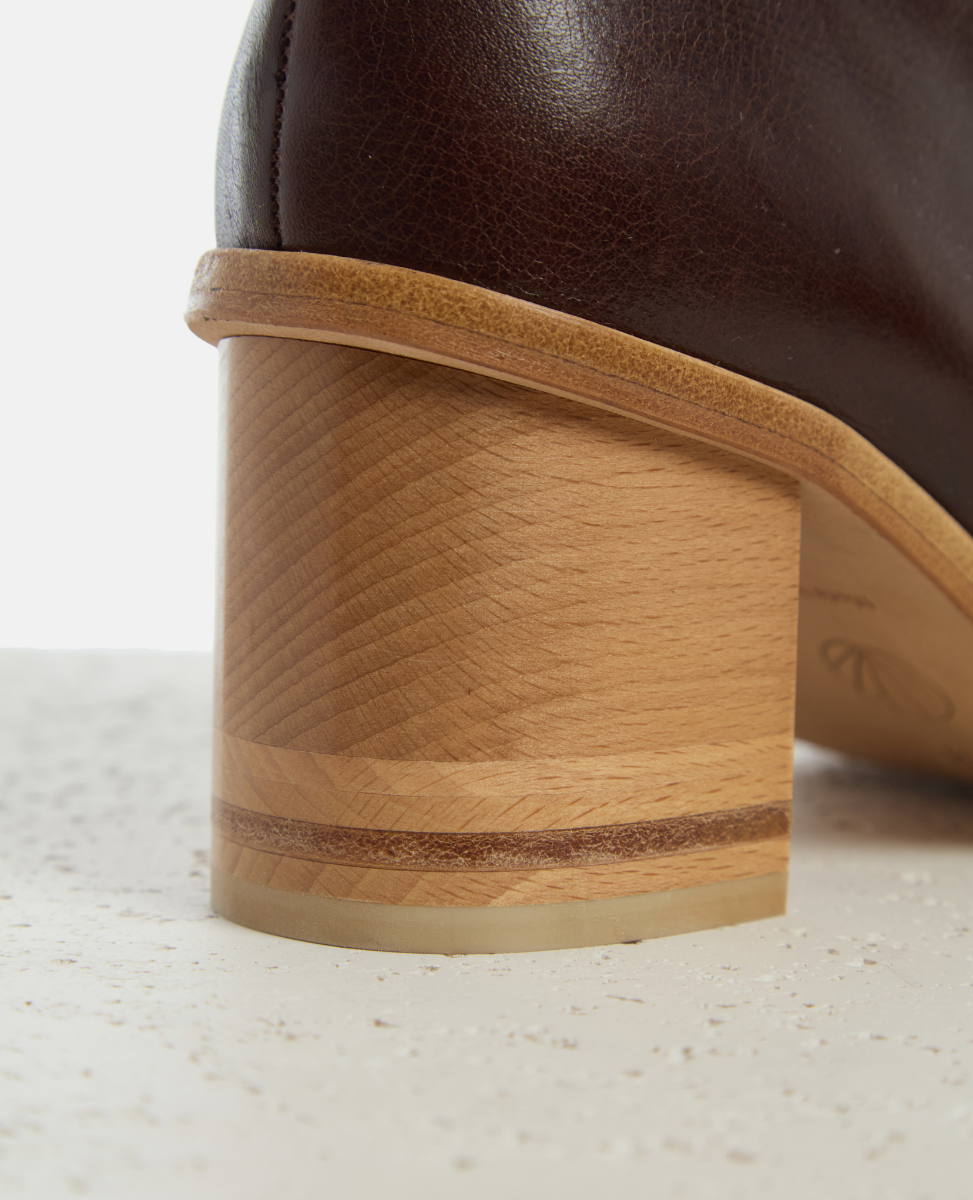 Close-up of a brown leather boot with wooden sole on a light background