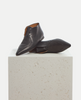 Pair of black leather shoes on a light gray pedestal 6