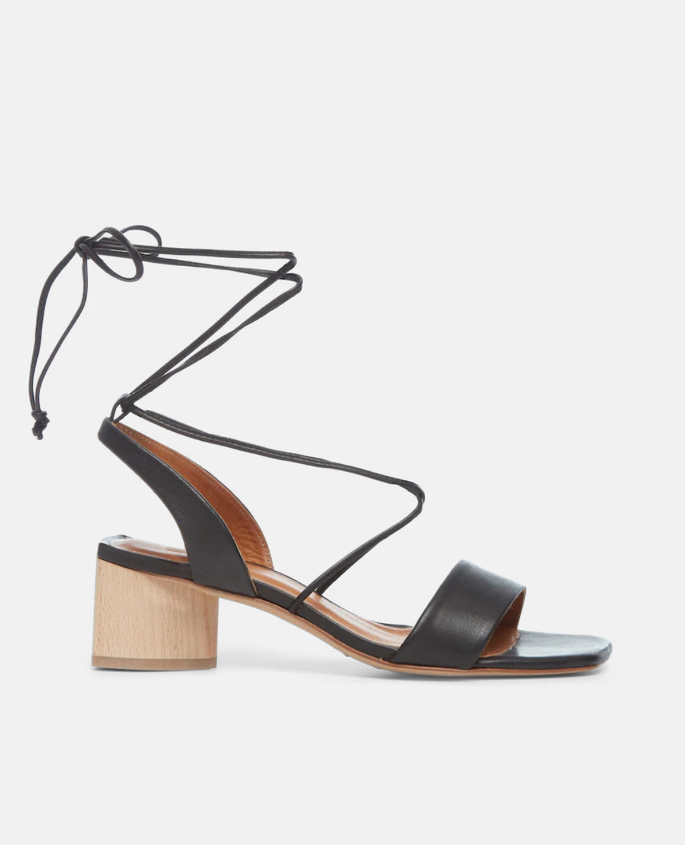 Side view of the Steph in Black Leather featuring a comfortable leather front band and a winding of leather straps that cascade up the ankle with a tie closure.