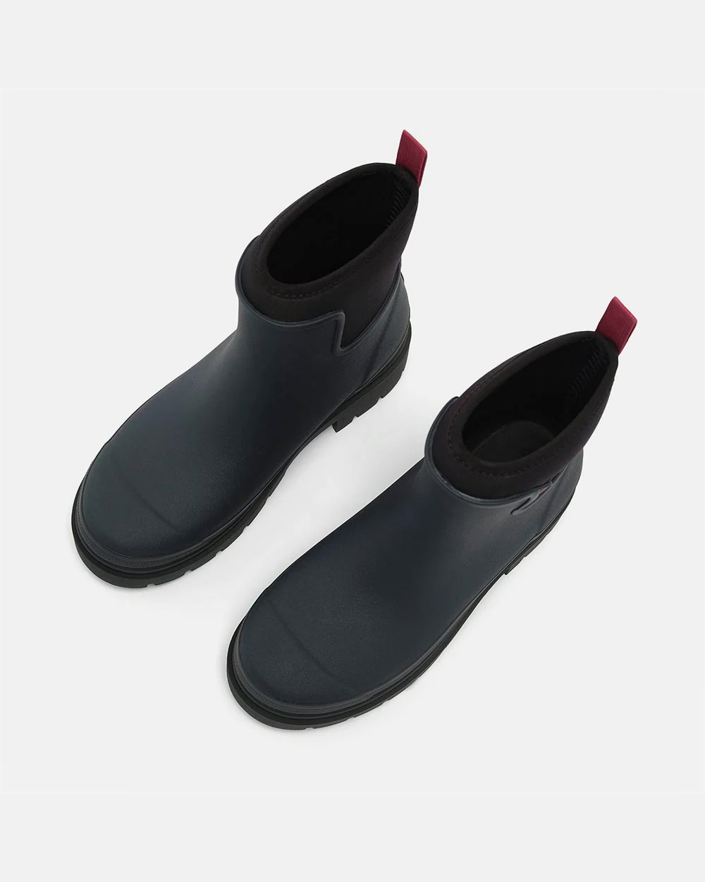 Pair of navy rubber ankle rain boots seen from above, showing black neoprene cuffs and berry pull tabs