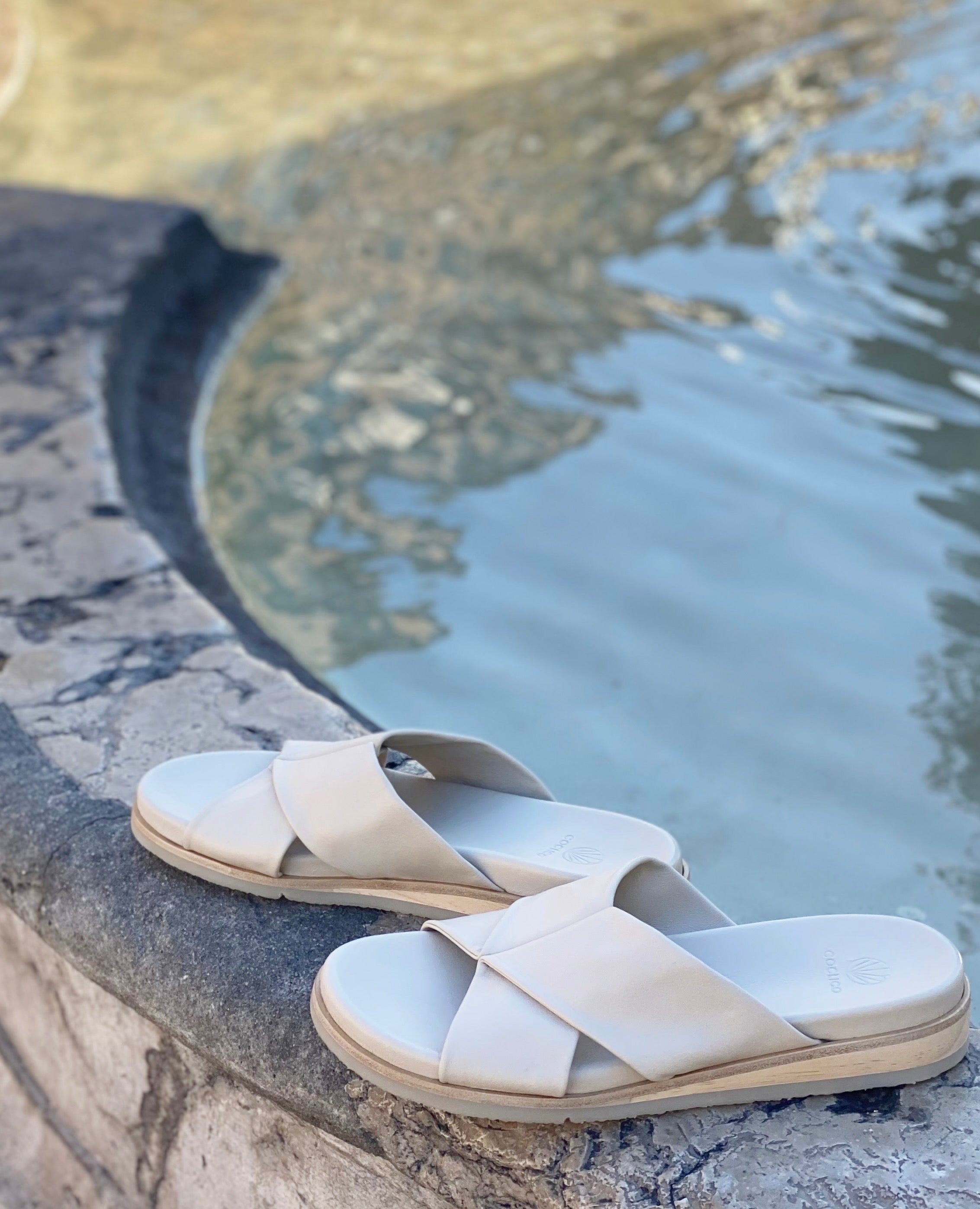 The Coclico pasque footbed slide sandal on a fountain in France