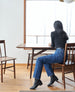 Woman sitting at a table wearing a black turtleneck, jeans, and the Miki Boot in Black. 4