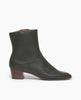 Side view of the Coclico Caviar Boot in Bosco leather, a simple & modern boot with a low-height wood block heel, inside zip closure and tall shaft height. 1