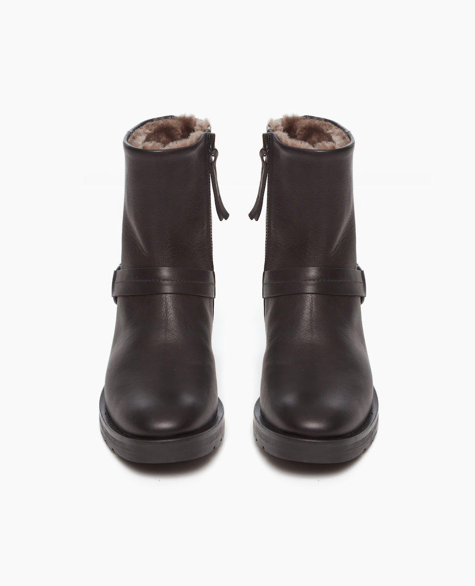 Damiana Shearling Boot displayed from the front. The full shearling lined modern moto boot is centered above, featuring a belt and loop at the ankle, a lug sole, and an inside-zip closure.