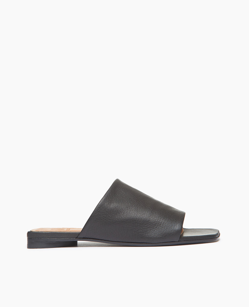 Side view of Coclico Ferhana Sandal in Black leather: flat slide-on style with one solid band of leather, squared-off at the toe and heel.