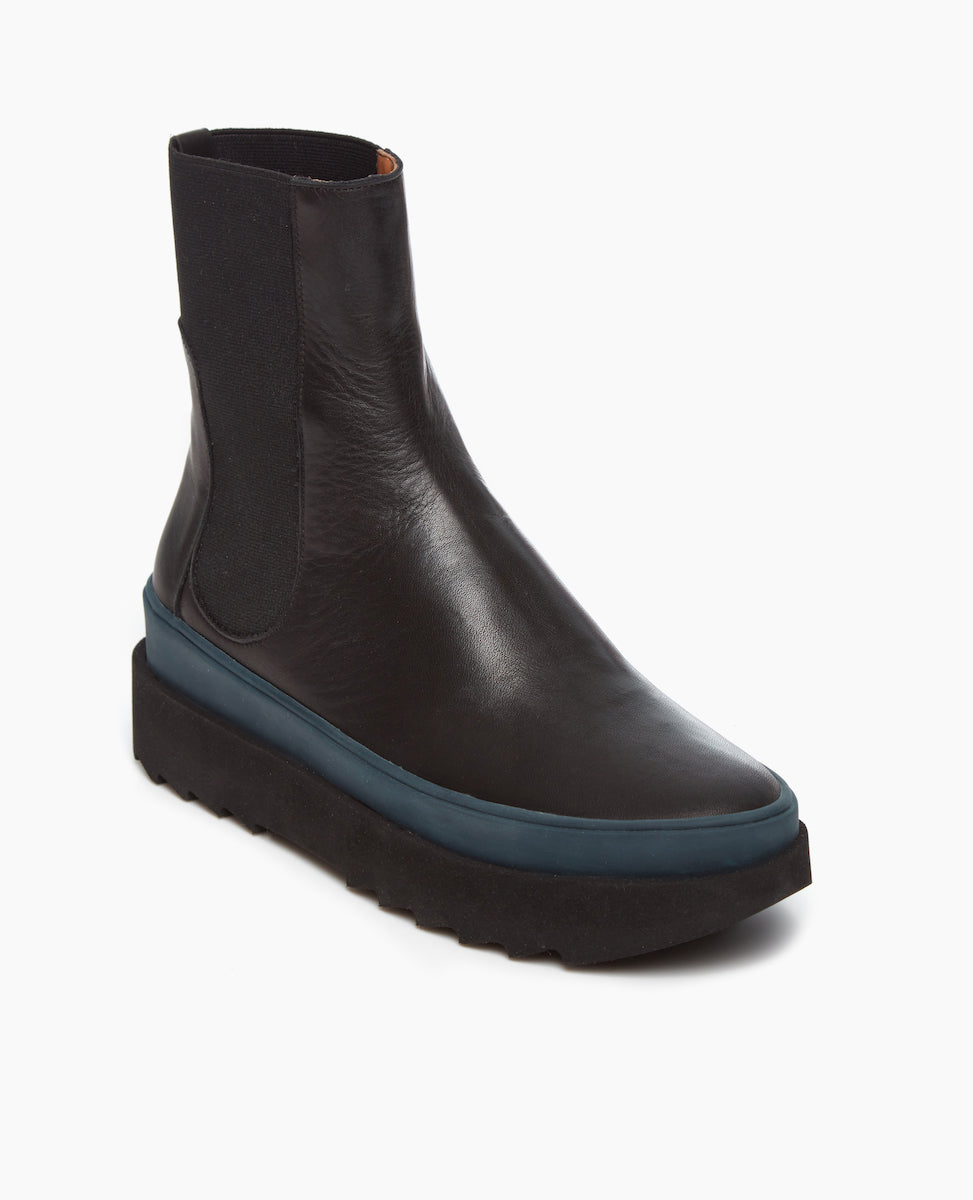Angled view of the France in Black leather: an easy pull-on chelsea boot with rubber midsole in teal, and toothed EVA out sole in black.