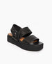Coclico Imna Wedge in Black leather, angled view: an open wedge with 2 tubular straps across foot, elasticated slingback strap, mid-height EVA  flatform sole. 2