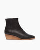Side view of the Java Boot in Black: featuring a solid wood low wedge with a slightly higher shaft and clean lines. Inside zip closure. 1