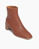 Angle view of Coclico Juju Boot in Caramello leather, a minimalist boot featuring an inside zip closure, soft squared-off toe, mid-height solid wood block heel, mid-height shaft. 2