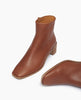 Close up, angle view shot of a minimalist boot featuring a mid-height solid wood block heel, inside zip closure, soft squared-off toe, mid-height shaft - Coclico Juju Boot in Caramello leather. 4