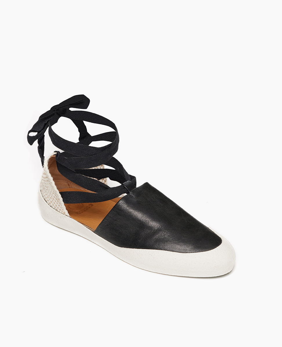 Coclico Kashm Sneaker in Black leather, angle view: unique flat-like feel sneaker with recycled rubber sole, leather upper secured with wide cotton laces that wind around the ankle.