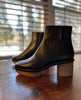 Side view of the Nigella Clog in Deep Sea placed on a wooden table with the sun shining through the blinds in the background. 5